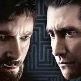 Primo piano dei volti intensi del cast di Prisoners, Hugh Jackman e Jake Gyllenhaal, con uno sfondo a labirinto.