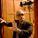 Martin Scorsese, con occhiali rossi, dirige sul set di Shutter Island. Le sue mani sono alzate, come a dare indicazioni.