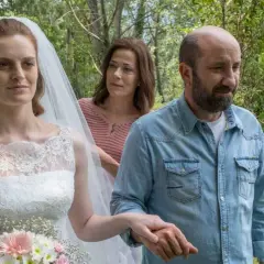 Sposa con velo e bouquet, accompagnata da un uomo in camicia di jeans e una donna sullo sfondo. Scena del **cento domeniche finale**.
