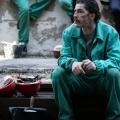 Uomo con baffi, in tuta verde, fuma una sigaretta. Le sue mani sono giunte, sembra pensieroso. Le recensioni per la palazzina LAF potrebbero essere simili.