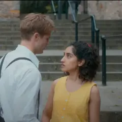 Un ragazzo e una ragazza si guardano intensamente su una scalinata. Le loro espressioni suggeriscono un momento carico di emozioni, forse l'inizio di una storia che troverà spazio nelle recensioni di un giorno.