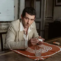 Un uomo con sigaretta in bocca accende un fiammifero, evocando l'atmosfera de "La Chimera recensione".