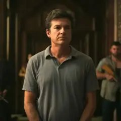 Un uomo con una polo grigia, circondato da uomini armati, ricorda il processo per omicidio del dentista di Pedro Pascal.