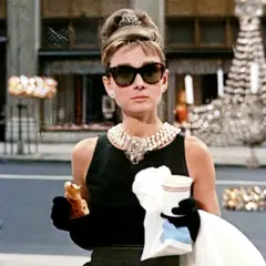 Holly Golightly, icona di stile, gusta un croissant davanti a Tiffany. Le sue recensioni su "Colazione da Tiffany" sarebbero sicuramente positive!