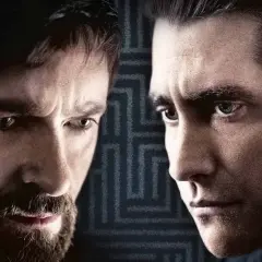 Primo piano dei volti intensi del cast di Prisoners, Hugh Jackman e Jake Gyllenhaal, con uno sfondo a labirinto.