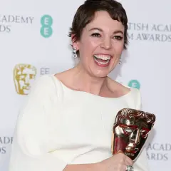 Olivia Colman, raggiante, celebra i suoi premi vinti da attrice, stringendo un BAFTA dorato.