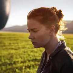 Donna con capelli rossi guarda un misterioso oggetto ovale fluttuante, simbolo dell'arrival linguaggio.