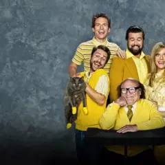 Il cast di "C'è sempre il sole a Philadelphia" posa sorridendo, con Charlie che tiene un gatto grigio con calzini gialli.