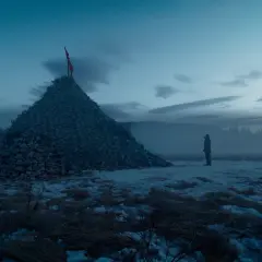 Un uomo solitario osserva un'enorme piramide di teschi in un paesaggio innevato. Un'immagine che evoca le recensioni de "The Revenant".