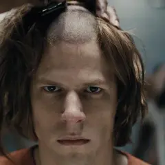 Un primo piano intenso di Jesse Eisenberg in un film, mentre gli rasano i capelli.