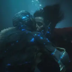 La forma dell'acqua recensione: un bacio subacqueo tra una donna e una creatura anfibia, illuminati da luci blu bioluminescenti.