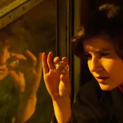 La doppia vita di Veronica: una ragazza guarda una biglia riflettendosi in un vetro, forse cercando risposte.
