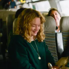 Una donna sorride mentre guarda un bambino su un treno. Le recensioni de "I figli degli altri" lodano questa scena.