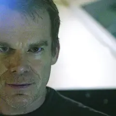 Primo piano di Dexter, con uno sguardo intenso. Le recensioni su Dexter lo descrivono come un personaggio complesso.
