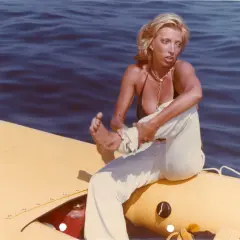 Donna bionda su un gommone giallo, travolta da un insolito destino curiosità, con il mare blu sullo sfondo.
