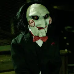 La maschera di Billy, il pupazzo di **jigsaw saw**, con i suoi vortici rossi e occhi rossi, indossa un abito elegante.