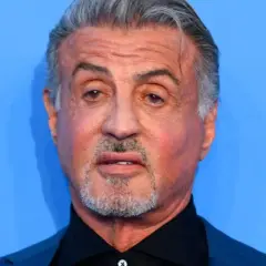 Sylvester Stallone, l'iconico Rocky Balboa oggi, con capelli grigi e barba corta, guarda intensamente.