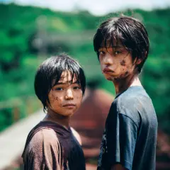 Due ragazzini sporchi di terra, con sguardi intensi, sembrano usciti da un film di mostri. Le loro espressioni suggeriscono storie che meritano recensioni.