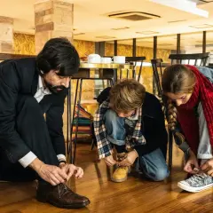 Padre e figli si allacciano le scarpe, un momento di vita quotidiana che merita recensioni positive per la sua semplicità.