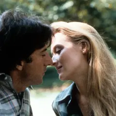 Un tenero momento tra John Cazale e Meryl Streep, i loro volti vicini in un abbraccio intimo.