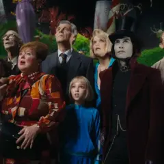 A group of children and adults, including Willy Wonka, look up in awe in a fantastical candy landscape.