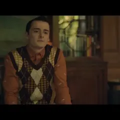 Il cast di The Tutor in un'ambientazione classica. Un giovane con un gilet a rombi su una camicia arancione.