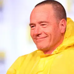 Bryan Cranston sorride con la sua iconica tuta gialla, ricordando le citazioni di Breaking Bad.