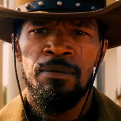 Primo piano di Django, con cappello da cowboy e barba. Il suo sguardo intenso evoca il significato di libertà e vendetta in Django Unchained.