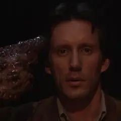 Un uomo con una mano mutata, simile a un tumore, punta alla tempia. Un'immagine disturbante che riflette il videodrome significato.