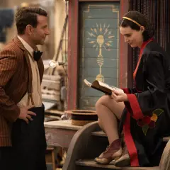 Uomo con giacca a righe e donna con vestito nero leggono un libro, forse la spiegazione de la fiera delle illusioni.
