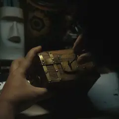 Mani che aprono un forziere, forse il tesoro di Gold Roger di One Piece. Sullo sfondo, una statua Moai e oggetti misteriosi.