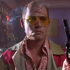 Un uomo con occhiali gialli, sigaretta e pistola, simbolo di paura e delirio a Las Vegas. Spiegazione visiva del caos.