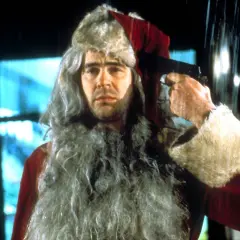Un uomo con barba e cappello da Babbo Natale tiene una pistola puntata alla tempia. Sembra una scena da "Una poltrona per due Babbo Natale".