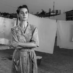 Una donna con un vestito a fiori fuma sul tetto, con panni stesi sullo sfondo. Le recensioni di "C'è ancora domani" lodano la sua interpretazione.