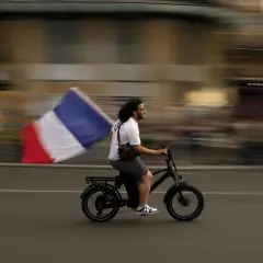 Uomo in bici sfreccia con bandiera francese, un'immagine che sfugge alle recensioni sull'odio.