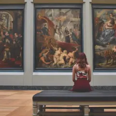 Una donna ammira tre grandi dipinti in un museo, forse colpita dalla sindrome di Stendhal.