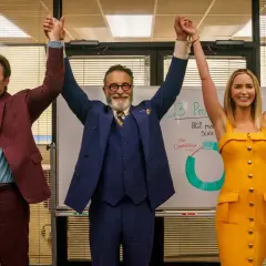 Tre persone celebrano un successo in ufficio, con un grafico alle spalle. Le recensioni di "Pain Hustlers - Il business del dolore" potrebbero descrivere questa scena.
