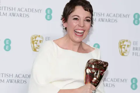 Olivia Colman, raggiante, celebra i suoi premi vinti da attrice, stringendo un BAFTA dorato.