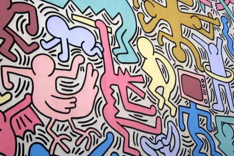 Un'esplosione di figure stilizzate e colorate, un'iconica opera di Keith Haring che celebra la vita e il movimento.