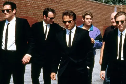 Sei uomini in abito nero camminano in gruppo, un cast cinematografico iconico.