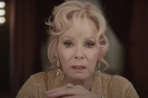 Jean Smart, parte del cast di Babylon, con un'espressione intensa e gioielli scintillanti.