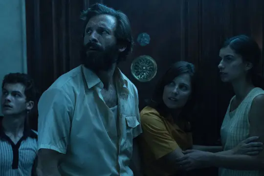 Quattro persone spaventate in un ambiente buio, forse in fuga da qualcosa. La scena evoca la tensione di "Possession: L'appartamento del diavolo storia vera".