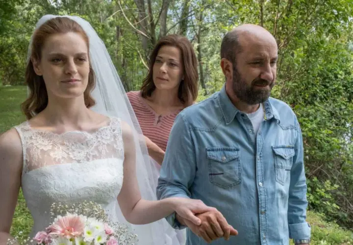 Sposa con velo e bouquet, accompagnata da un uomo in camicia di jeans e una donna sullo sfondo. Scena del **cento domeniche finale**.