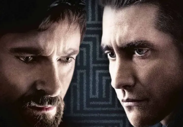Primo piano dei volti intensi del cast di Prisoners, Hugh Jackman e Jake Gyllenhaal, con uno sfondo a labirinto.