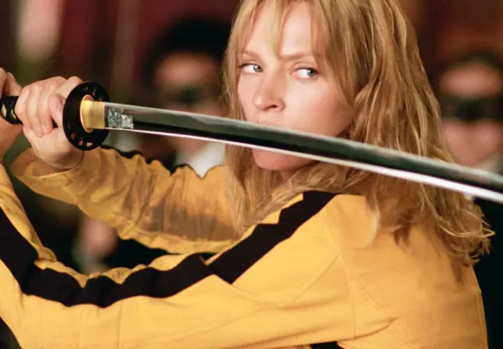 La Sposa, con la sua iconica tuta gialla, impugna la katana. Il suo sguardo è intenso, pronto a vendicarsi. Kill Bill: la benda sull'occhio è un monito.