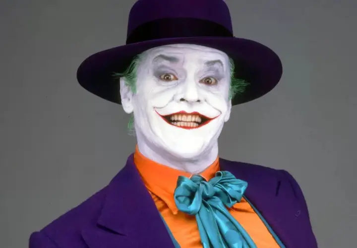 Jack Nicholson nel suo iconico ruolo di Joker, primo film, con trucco bianco, capelli verdi e cappello viola.