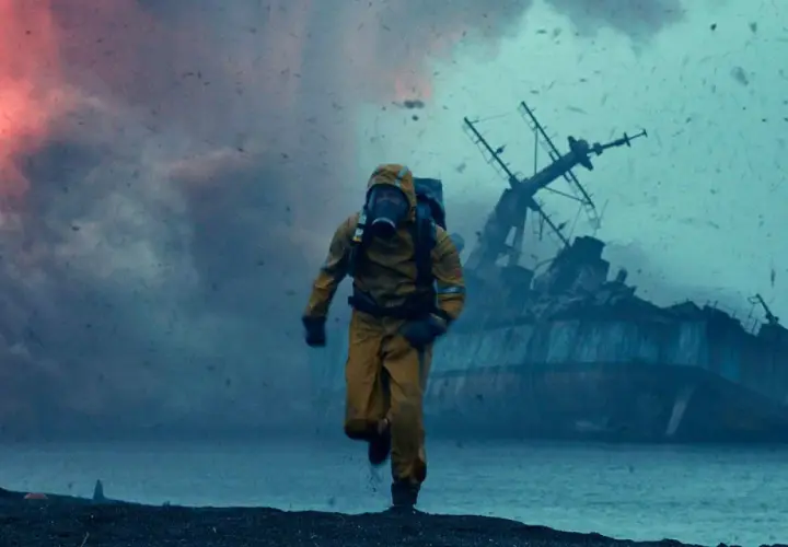Uomo in tuta gialla corre su una spiaggia desolata, con una nave naufragata sullo sfondo. Le recensioni di Greenland descrivono scene apocalittiche simili.