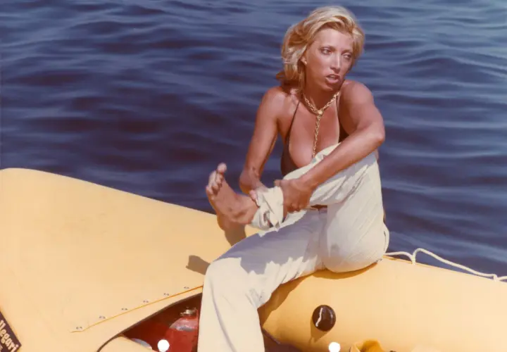 Donna bionda su un gommone giallo, travolta da un insolito destino curiosità, con il mare blu sullo sfondo.