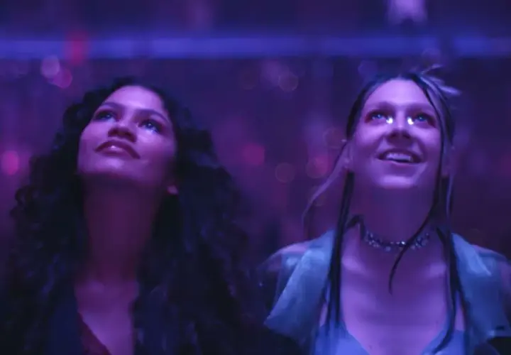 Due ragazze, immerse in luci viola, vivono un momento di pura **euforia 2**.