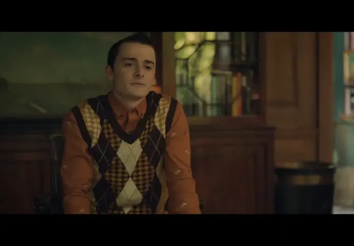 Il cast di The Tutor in un'ambientazione classica. Un giovane con un gilet a rombi su una camicia arancione.